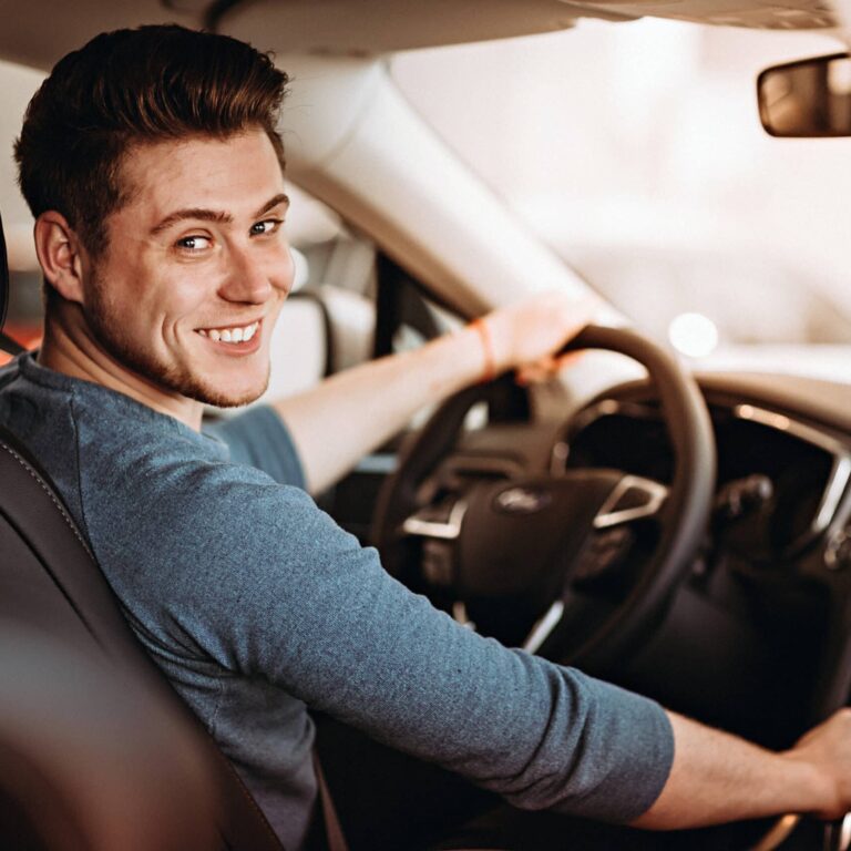Happy young driver behind the wheel of a car. Buying a car and driving concept.